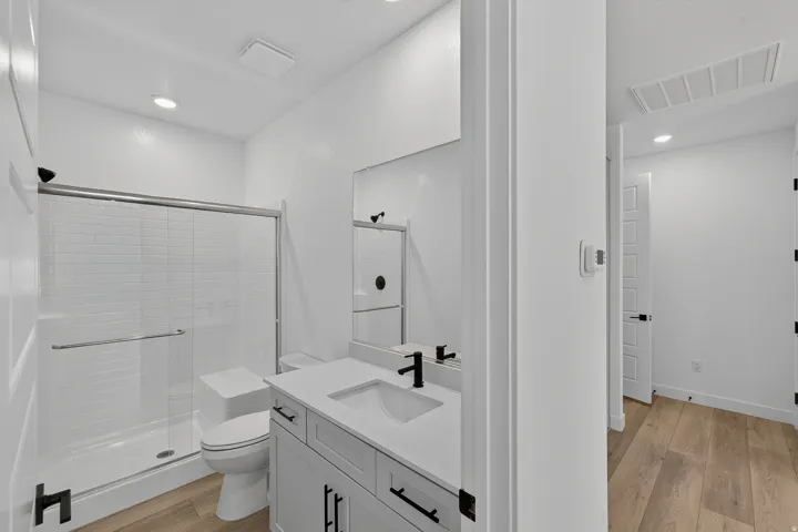 Modern primary bathroom featuring a floating vanity with dual rectangular vessel sinks, quartz countertop, and matte black hardware
