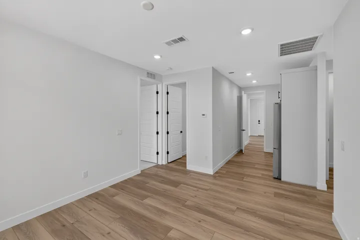 Open-concept living area featuring wood-finish flooring, recessed lighting, white walls, and white baseboards