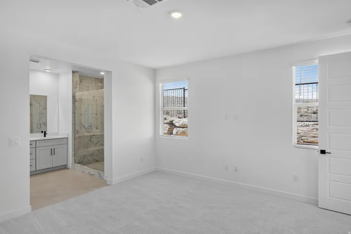 Primary Bedroom Suite featuring neutral carpet flooring, recessed ceiling lighting, and dual windows with natural light