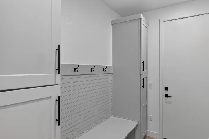 Entryway featuring built-in cabinetry, integrated bench seating, wall-mounted coat hooks, and a paneled accent wall