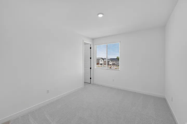 Bright room featuring a window with horizontal blinds, neutral wall paint, recessed lighting, and grey carpeting