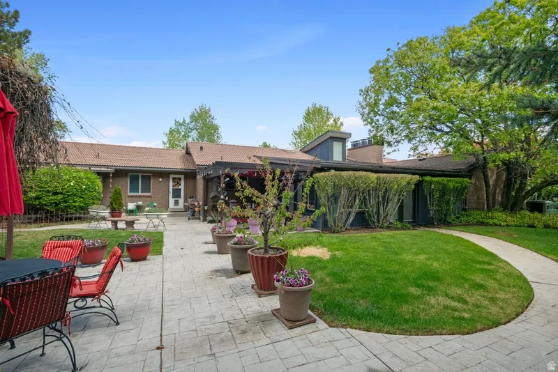 Rear view of house with a lawn, a patio, brick siding, and a tile roof
