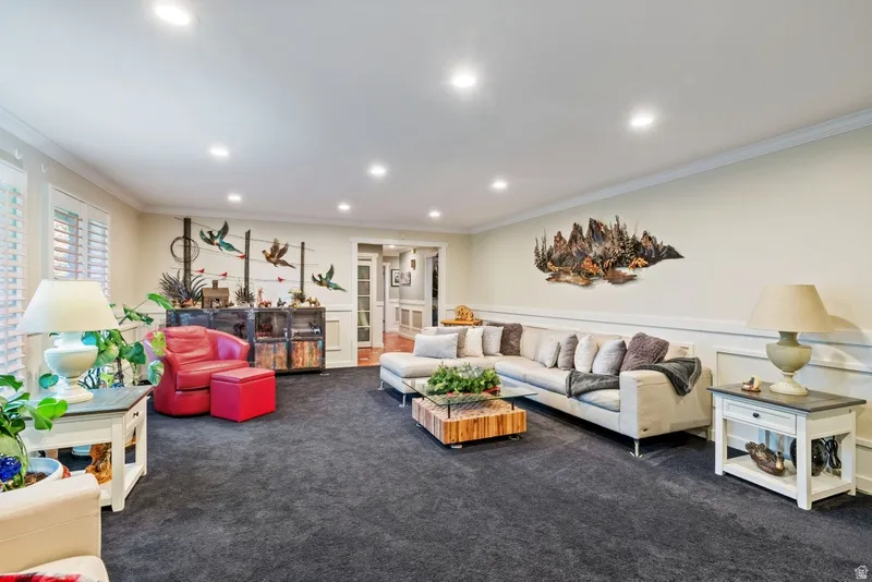Living area featuring dark colored carpet, crown molding, recessed lighting, and wainscoting