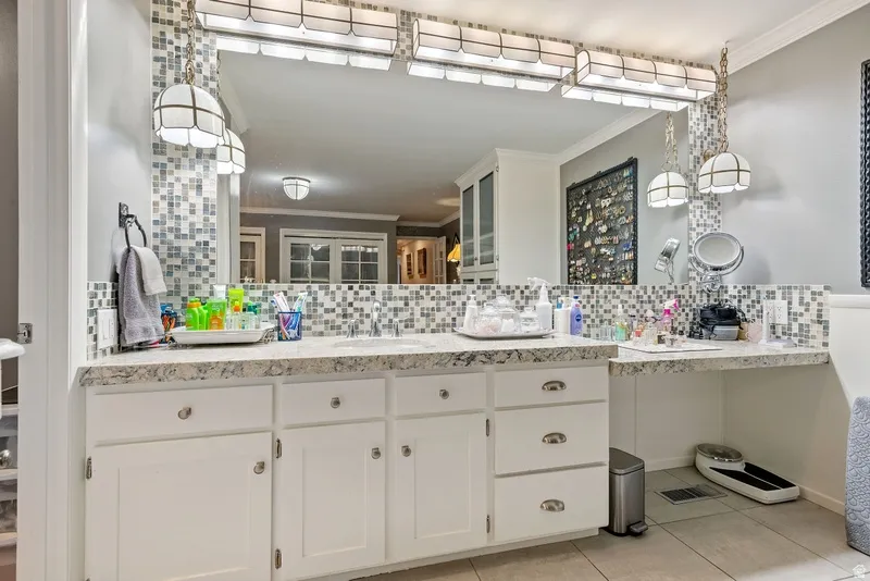 Bathroom featuring vanity, ornamental molding, decorative backsplash, and light tile patterned floors