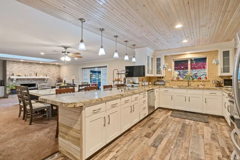 Kitchen with a peninsula, a fireplace, white cabinetry, crown molding, and wood ceiling