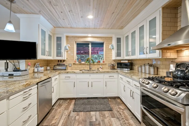 Kitchen featuring white cabinetry, glass fronted cabinets, light wood finished floors, stainless steel appliances, and light stone countertops