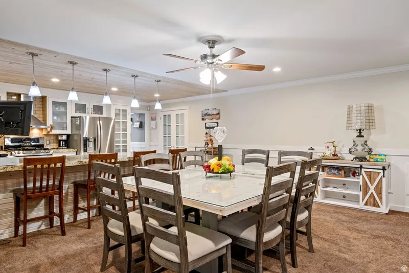 Dining space featuring wainscoting, light colored carpet, recessed lighting, ceiling fan, and ornamental molding