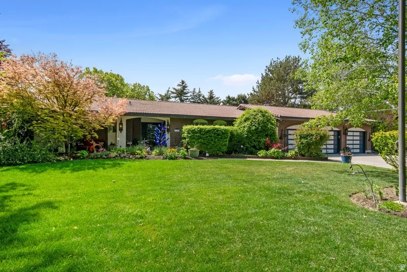 Ranch-style house with a front yard, a tiled roof, stucco siding, and concrete driveway
