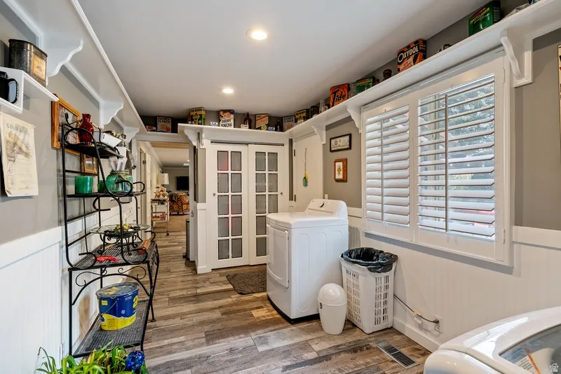 Laundry room with a wainscoted wall, light wood finished floors, washing machine and clothes dryer, and recessed lighting