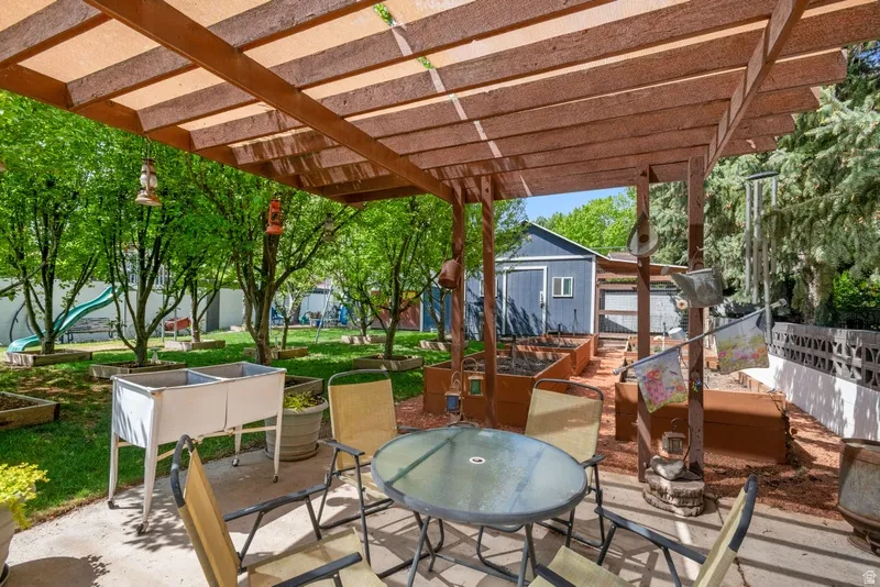 View of patio featuring outdoor dining area, a vegetable garden, and an outbuilding