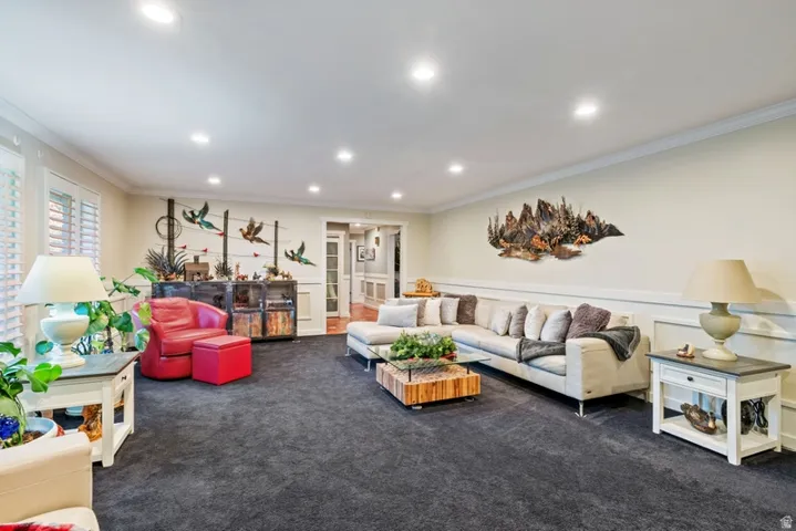 Living area featuring dark colored carpet, crown molding, recessed lighting, and wainscoting