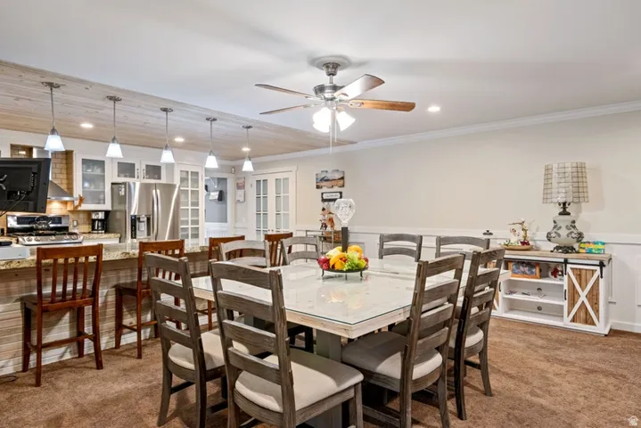 Dining space featuring wainscoting, light colored carpet, recessed lighting, ceiling fan, and ornamental molding