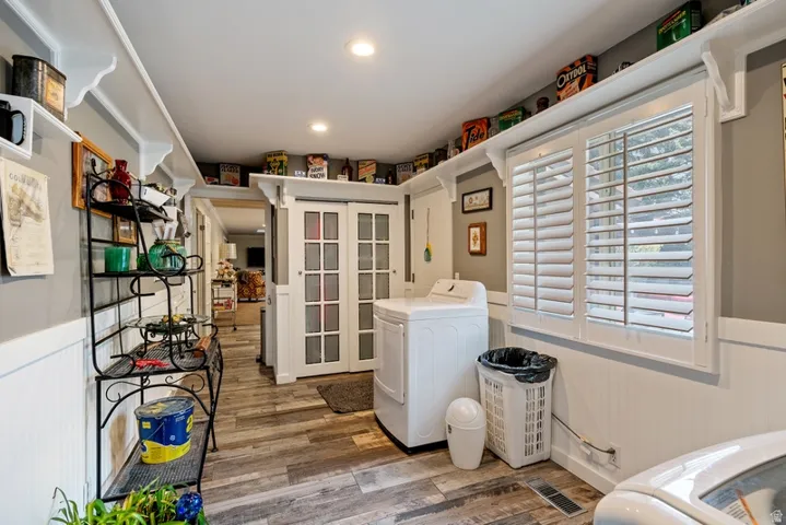 Laundry room with a wainscoted wall, light wood finished floors, washing machine and clothes dryer, and recessed lighting