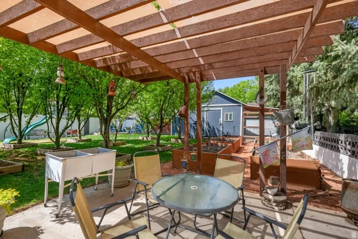 View of patio featuring outdoor dining area, a vegetable garden, and an outbuilding