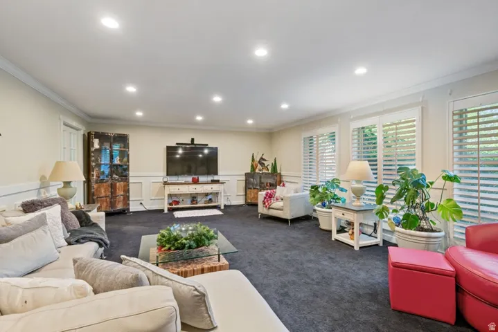 Living area featuring dark colored carpet, ornamental molding, recessed lighting, and wainscoting