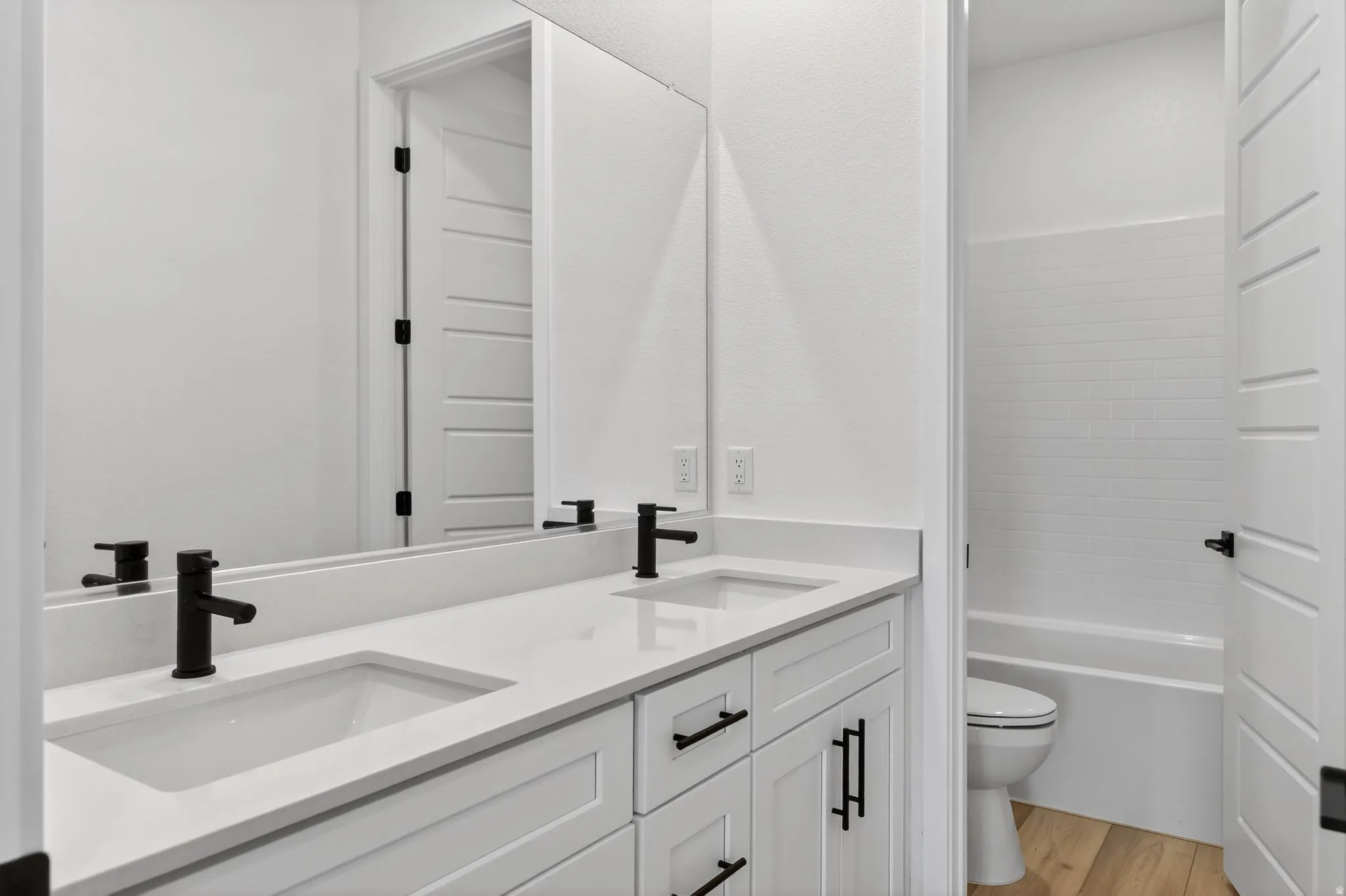 Bathroom with double vanity and light wood-type flooring