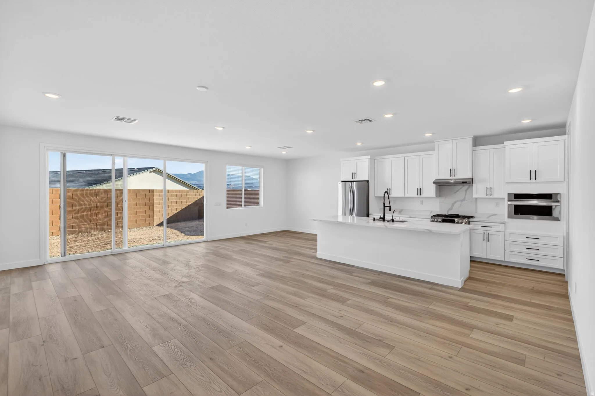 Kitchen featuring white cabinets, an island with sink, stainless steel appliances, light wood-style flooring, and recessed lighting