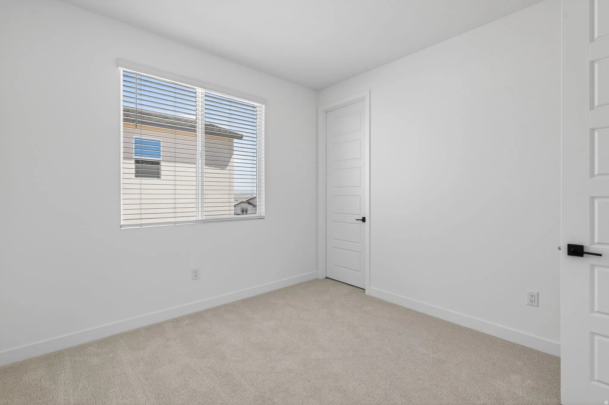 Empty room with light carpet and baseboards