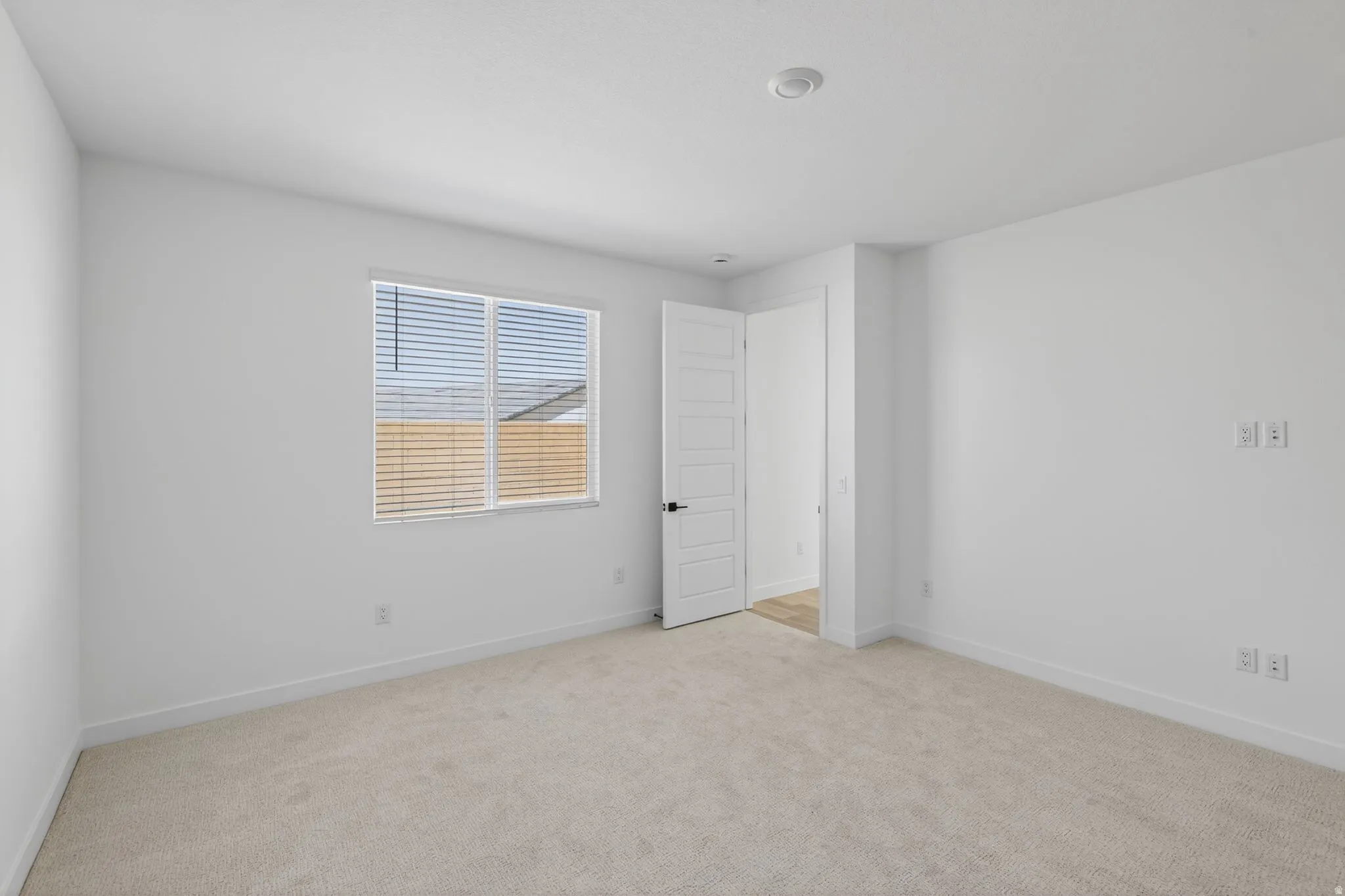 Unfurnished bedroom with light colored carpet and baseboards