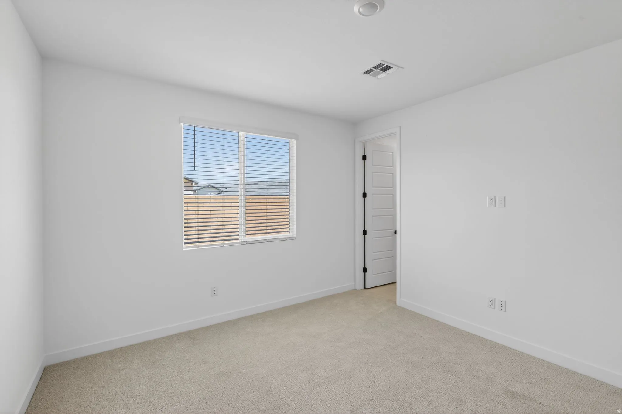 Empty room featuring light carpet and baseboards