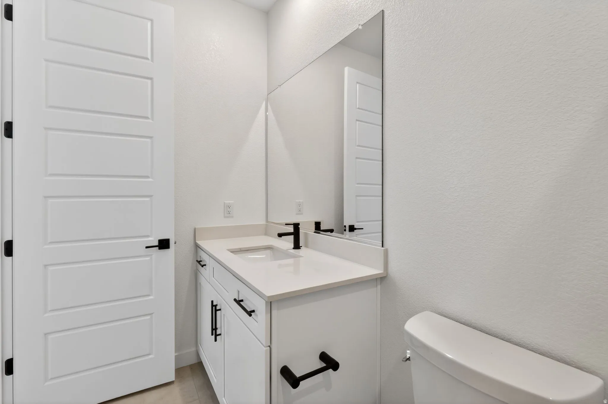Bathroom featuring a textured wall and vanity