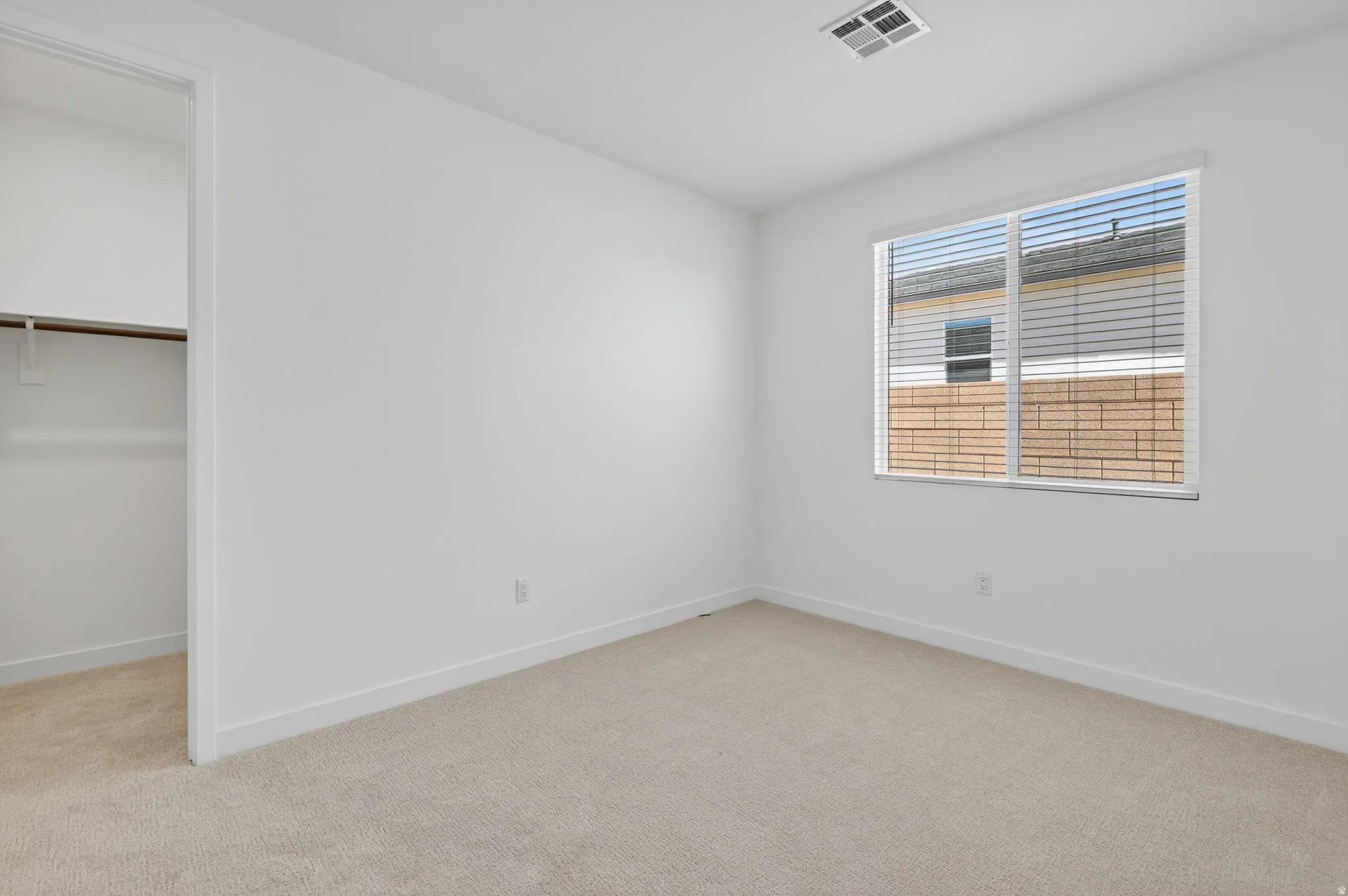 Unfurnished bedroom with a spacious closet and light colored carpet