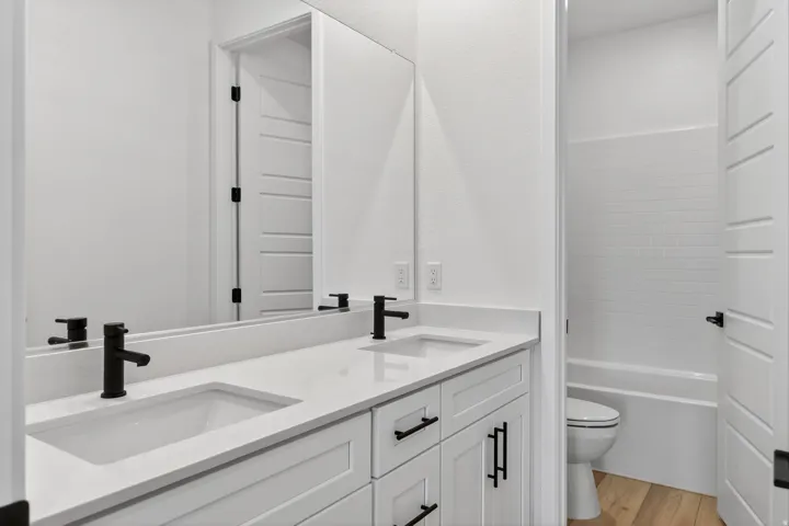 Bathroom with double vanity and light wood-type flooring