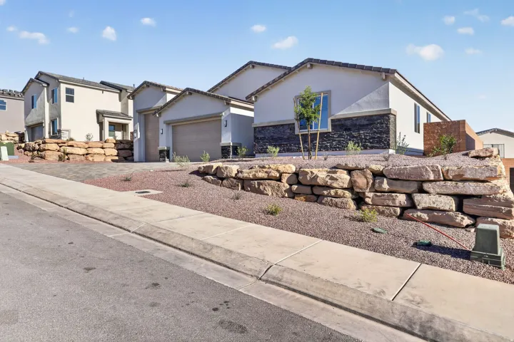 View of front facade with stucco siding, stone siding, an attached garage, and driveway
