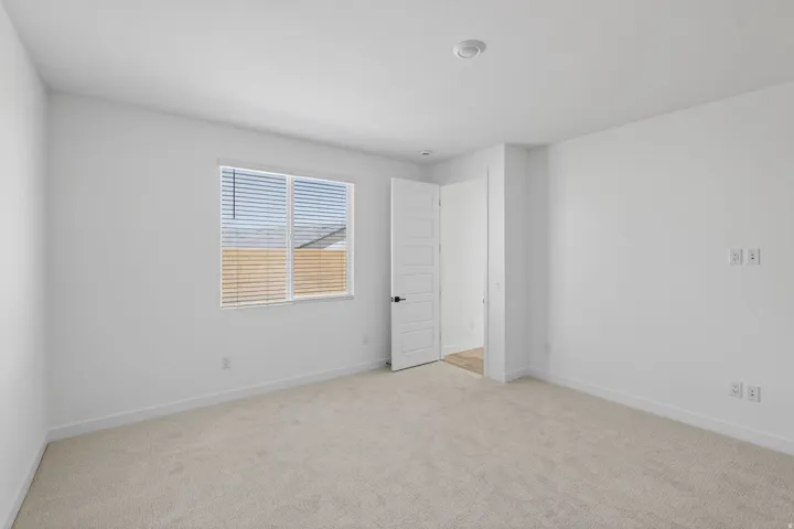 Unfurnished bedroom with light colored carpet and baseboards