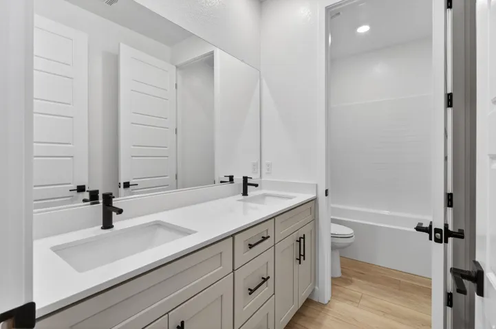 Bathroom with double vanity, light wood-style floors, and recessed lighting