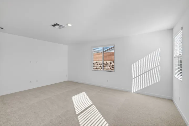 Empty room with light colored carpet and recessed lighting