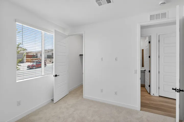 Unfurnished bedroom with a walk in closet and light colored carpet