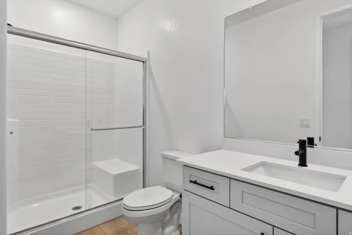 Full bath with vanity, a stall shower, and light wood finished floors