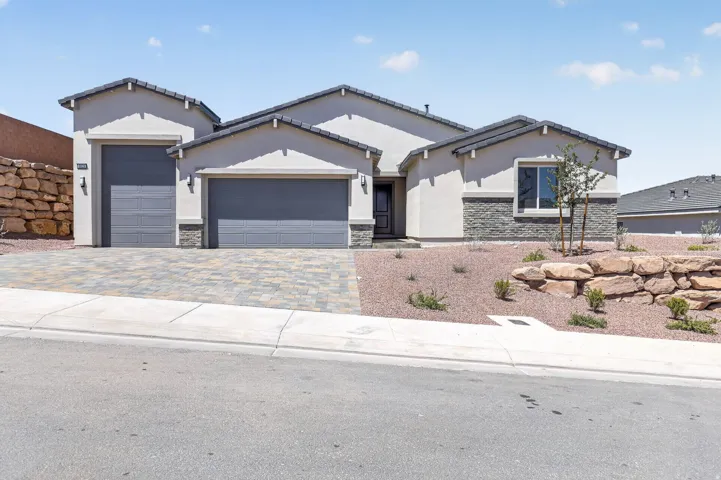 Ranch-style home with stone siding, a garage, stucco siding, and driveway