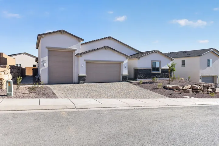 View of front facade featuring a garage, driveway, stucco siding, and a tiled roof