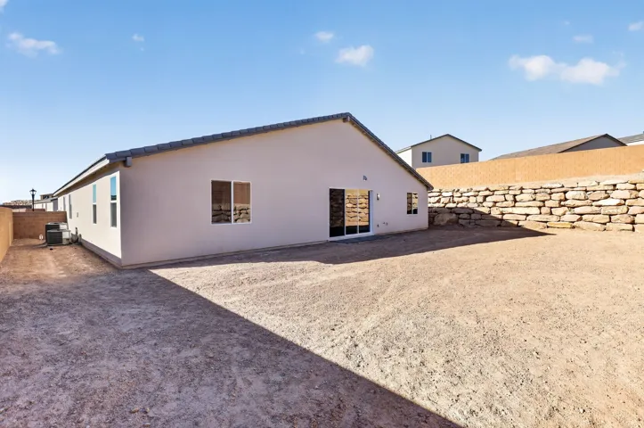 Back of property with a fenced backyard and stucco siding