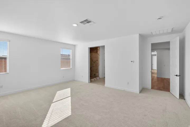 Unfurnished bedroom with light carpet, ensuite bath, and recessed lighting