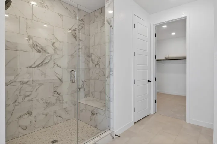 Bathroom featuring a marble finish shower, a spacious closet, and recessed lighting