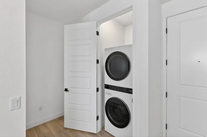 Laundry area featuring light wood-style floors and stacked washer and dryer