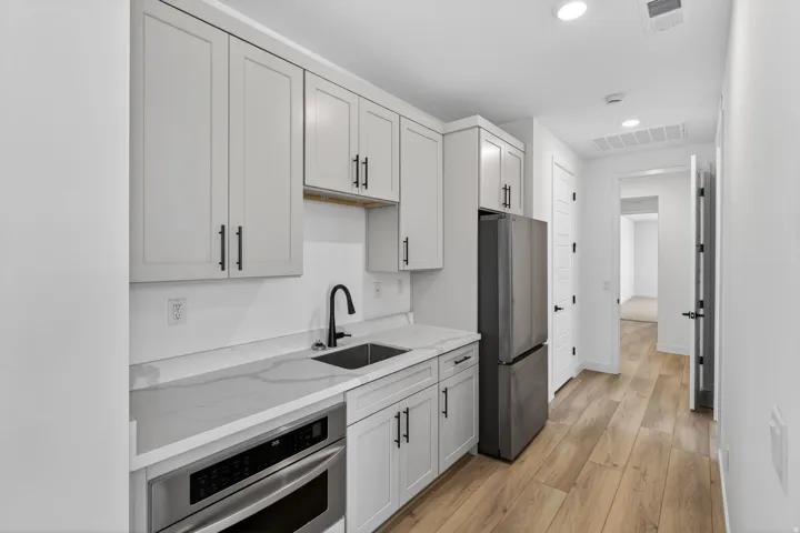 Kitchen with stainless steel appliances, light stone counters, light wood-type flooring, and recessed lighting