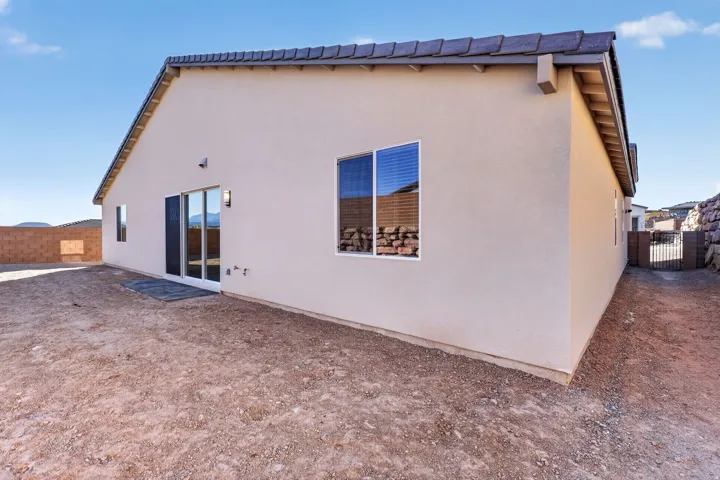 Back of house with stucco siding and a gate