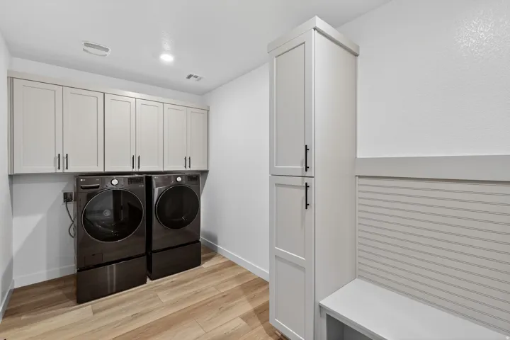 Laundry area featuring light wood-type flooring, washer and clothes dryer, and cabinet space