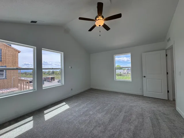 Carpeted empty room with ceiling fan and baseboards