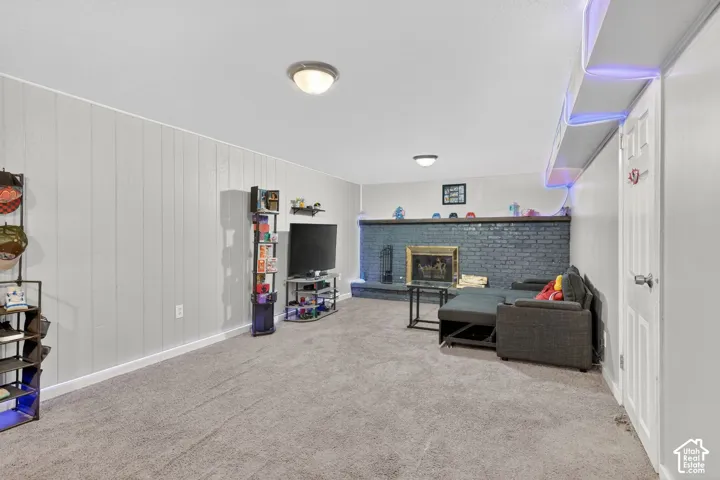 Living area featuring a fireplace, light carpet, and wood walls