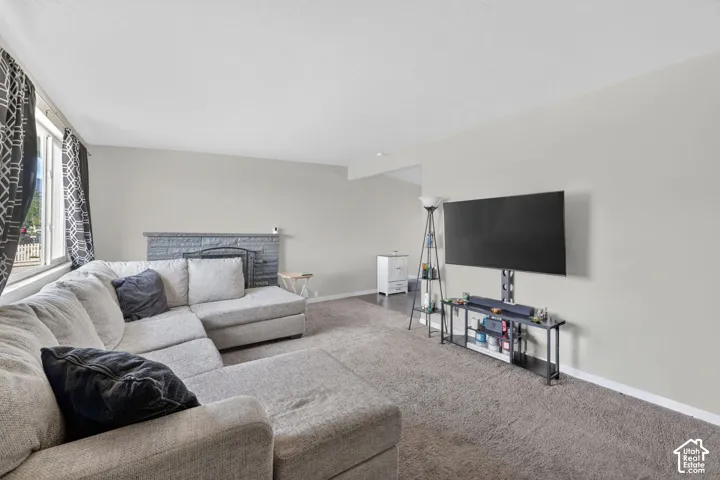 Carpeted living room featuring baseboards and a fireplace