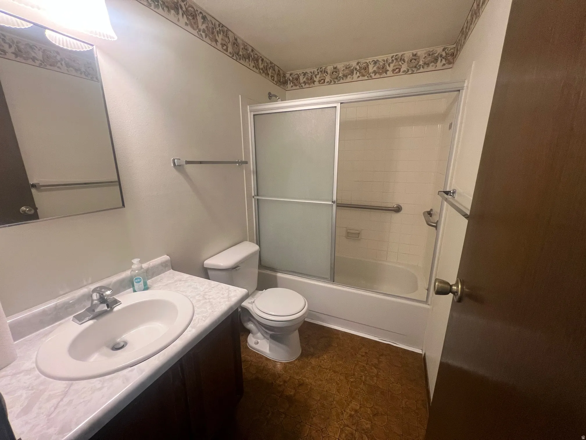 Full bathroom with vanity and shower / bath combination with glass door on the main floor