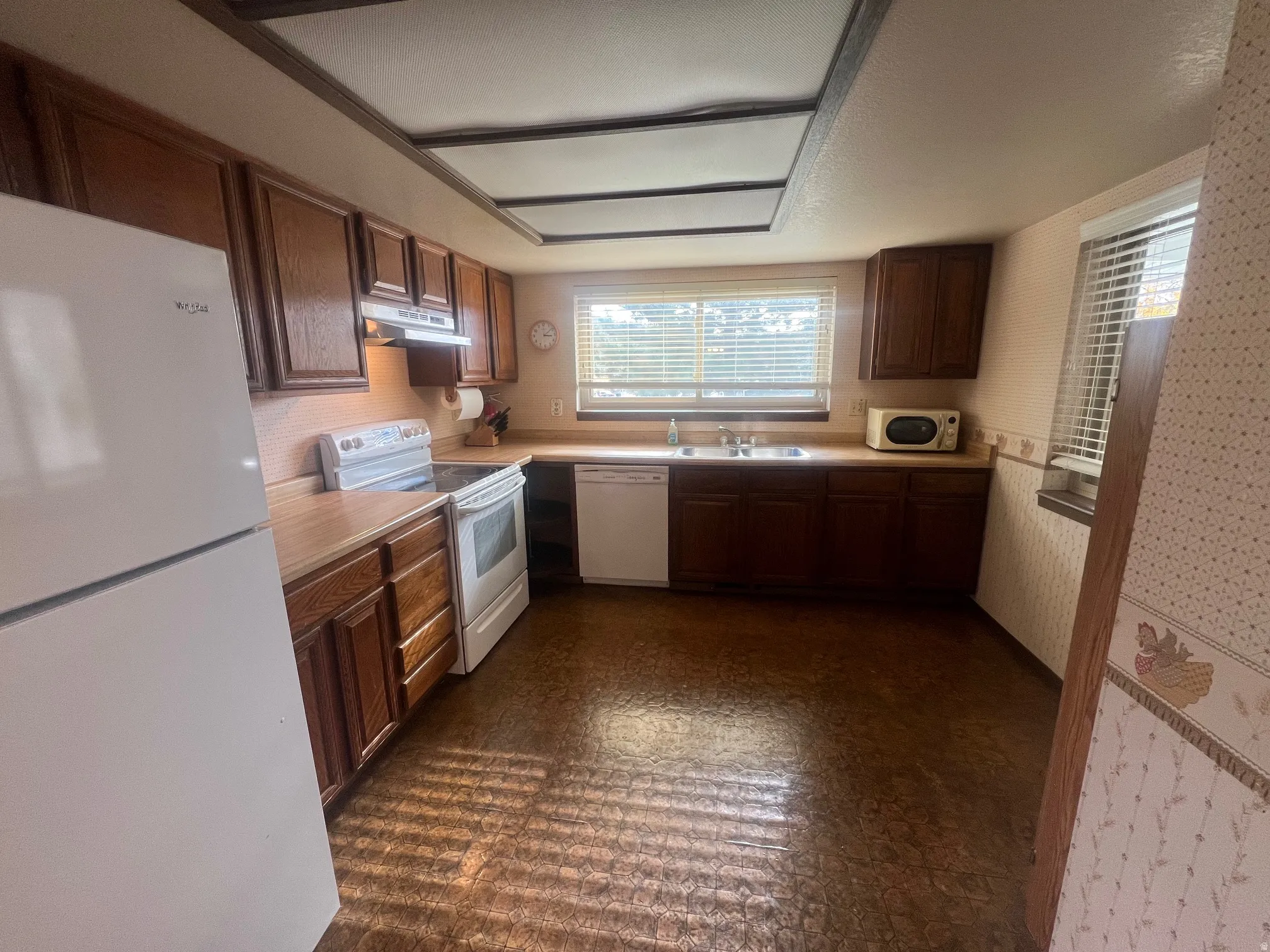 Kitchen with white appliances, plenty of natural light, light countertops, dark floors