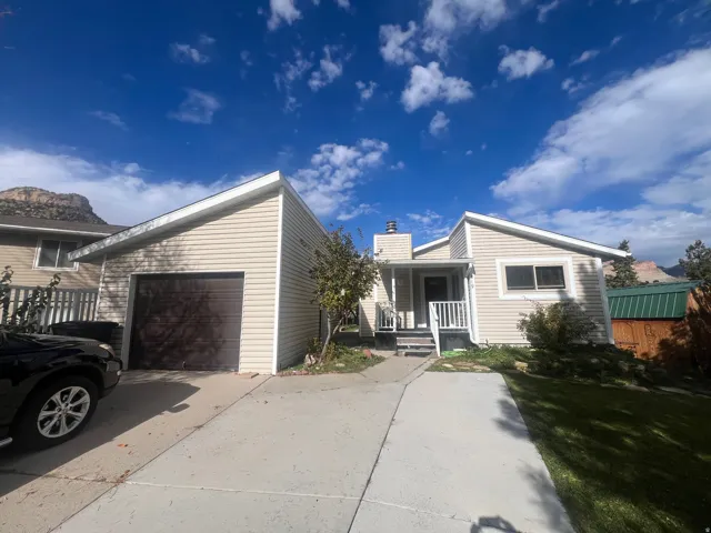 Rambler style home featuring a porch, a chimney, driveway, and a garage