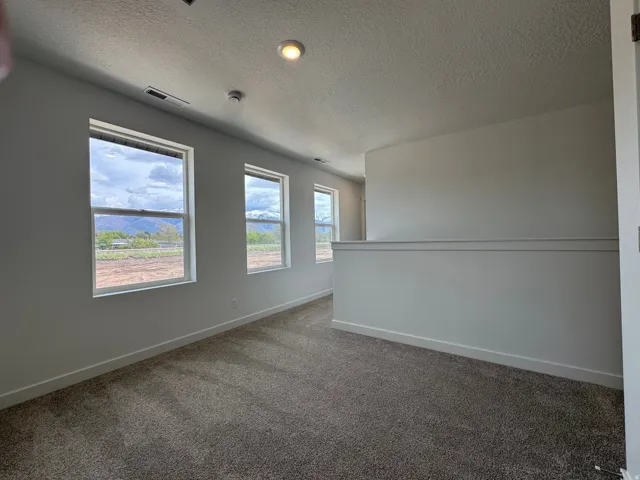 Unfurnished room with dark carpet and a textured ceiling