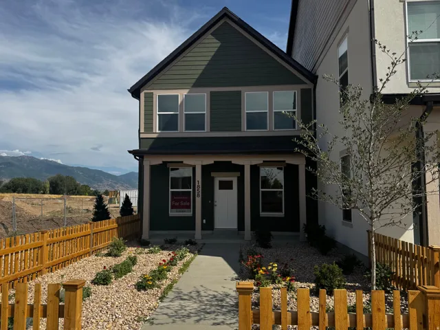 Two-story residence featuring dark green siding with black trim, a white front door, and a covered porch entry